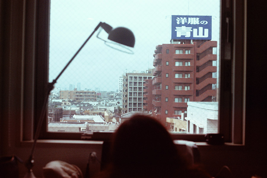 A girl doing her makeup beside a window in a Tokyo hotel room