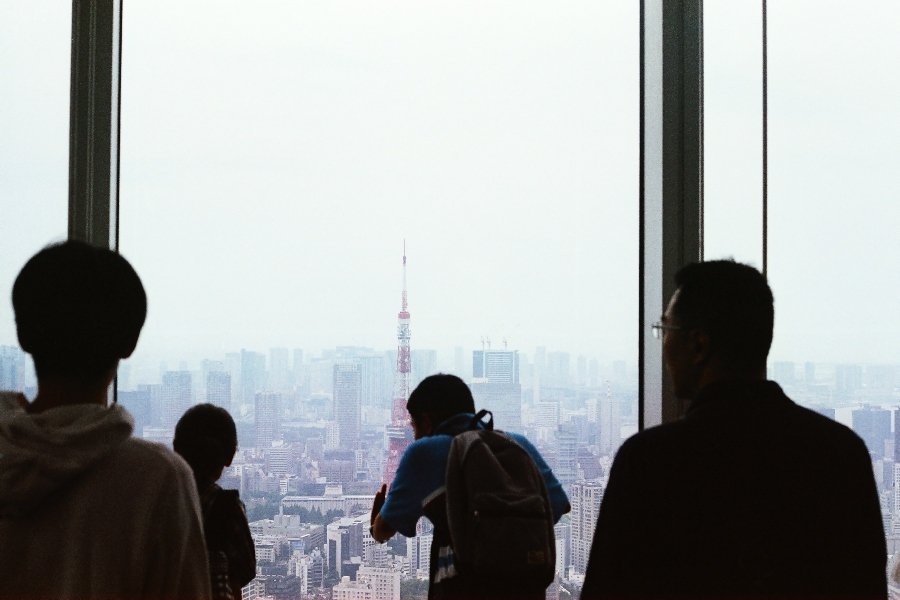 People looking over Japan's skyline from the skytree with Tokyo tower in the distance